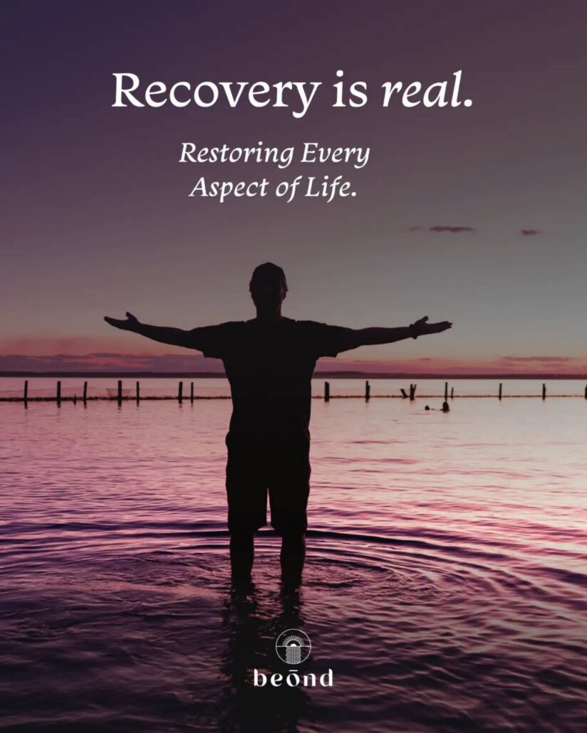 Person standing in water with arms outstretched at sunset, symbolizing recovery and the restoration of a life.
